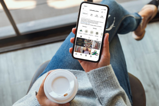 Student holding iphone with University of South Florida (Online Chapter) Instagram account on screen